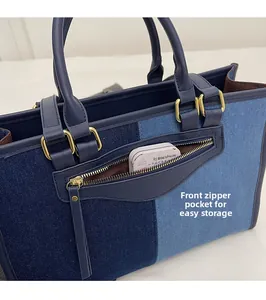 Detail view of the functional front zipper pocket on this two-tone denim tote bag