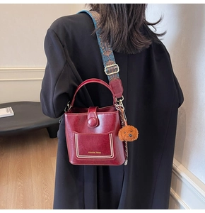 Modell mit burgunderroter Beuteltasche, ethnischem Schultergurt und Pudel-Anhänger im Detail