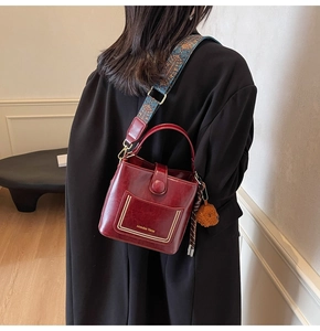 Detail der burgunderroten Beuteltasche mit Vintage-Leder und ethnischem Webgurt