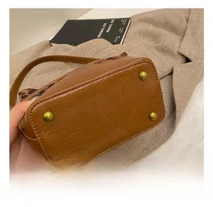Detail showing the brown leather handbag base with four golden metal protective feet studs