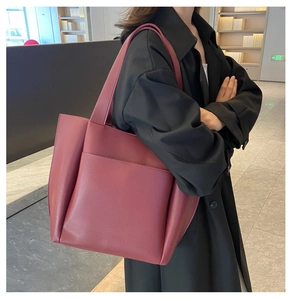 Close-up of deep red leather tote bag with large front pocket and wide shoulder straps