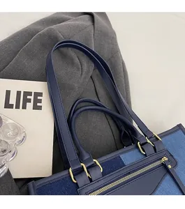 Detail of blue denim tote bag with gold zipper and contrast stitching on fabric