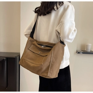 Macro detail of brown canvas crossbody bag with wide black strap and silver metal buckle