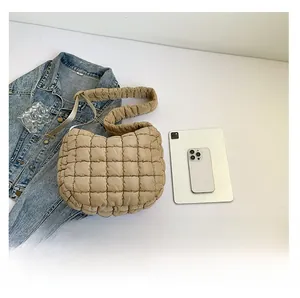 Detail of beige quilted puffer bag featuring a pleated texture and modern cloud design