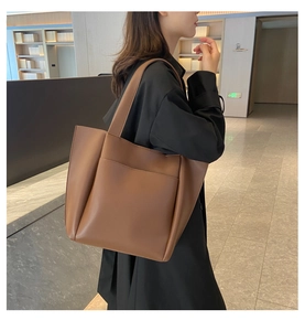 Brown leather tote bag featuring a front pocket and wide strap for stylish daily commuting