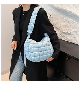 Close-up of light blue quilted crossbody bag with adjustable strap and puffy texture