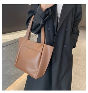 Detail showing brown faux leather tote bag with external pocket and reinforced stitching