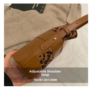Detailed close-up of brown leather strap with gold buckle on leopard print bucket bag