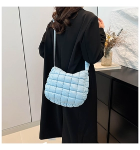 Quilted puffer tote bag in light blue nylon fabric shown on shoulder of a model