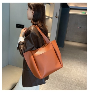 Close-up of caramel brown tote bag featuring litchi grain leather and large front pocket