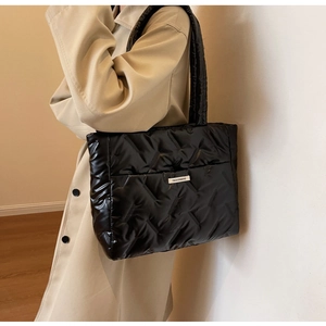 Détail du sac cabas noir matelassé montrant la texture bouffante et l'étiquette logo