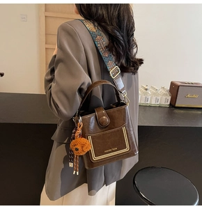 Detail der braunen Vintage-Beuteltasche mit Ethno-Gurt und süßem Bären-Anhänger