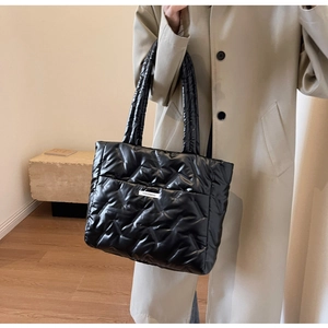 Détail du grand cabas noir matelassé avec étiquette tendance et bandoulières rembourrées