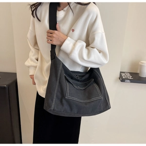 Detail of black canvas messenger bag with contrast white stitching and wide strap