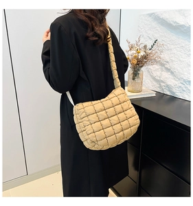 Detail of khaki quilted puffer tote bag on shoulder with light nylon fabric texture