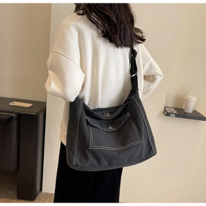 Nahaufnahme einer anthrazitfarbenen Canvas-Tasche mit weißen Kontrastnähten und Tragegurt
