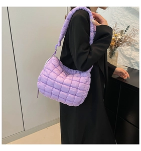 Close-up of purple quilted puff shoulder bag on model with padded fabric texture