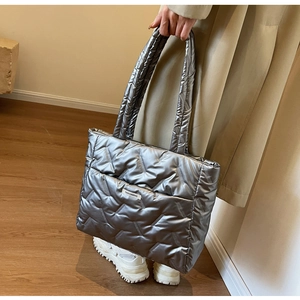 Détail du sac cabas matelassé argenté avec surpiqûres en chevron et étiquette de mode