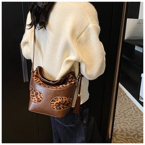 Detail view of a vintage leopard print bucket bag with fringe tassel and brown leather