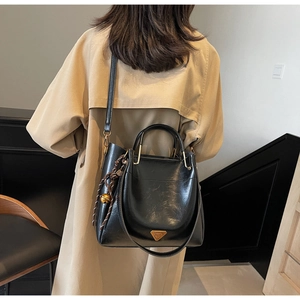 Close-up of black textured leather shoulder bag featuring gold hardware and bell detail