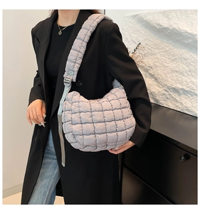 Macro view of light gray puffer bag featuring quilted fabric and adjustable wide strap