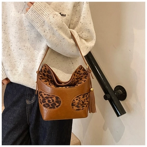 Detail of vintage brown leather bucket bag with leopard print and fringe tassel on model