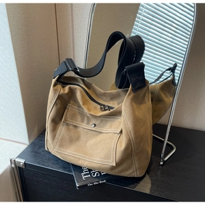 Detail of khaki canvas messenger bag featuring contrast white stitching and wide strap