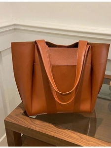 Caramel lychee grain tote bag with large capacity and front pocket on a wooden table