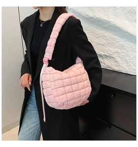 Close-up of pink quilted cloud bag with adjustable strap worn on a black blazer
