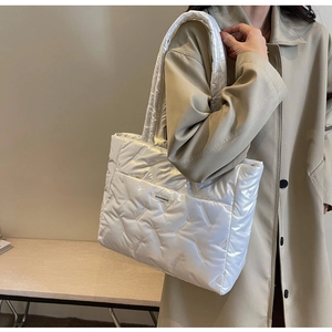 Détail de la large bandoulière rembourrée et de la texture matelassée du cabas blanc perle