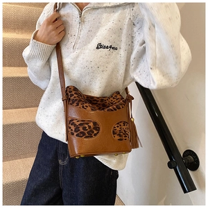 Detail of leopard print bucket bag featuring brown leather trim and side tassels