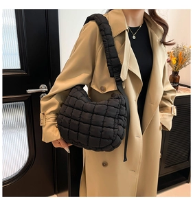 Detail of black quilted puffer tote bag showing soft textured fabric and wide shoulder strap