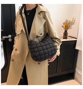 Close-up of black quilted puffer tote bag styled with a beige trench coat on a model