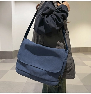 Seitenansicht der dunkelblauen Canvas-Umhängetasche mit verstellbarem Riemen am Model