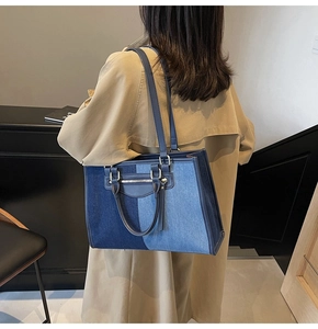 Detailed view of large denim patchwork tote bag with long tassels on a trench coat