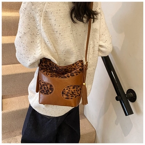 Detail of vintage brown bucket bag with leopard print stitching and long tassel charms