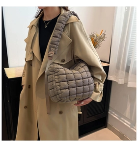 Detail of grey quilted puffy shoulder bag with adjustable strap on khaki trench coat