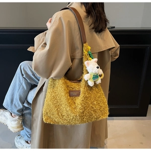 Detail of yellow plush tote bag with brown leather strap and cute white dog charm on model