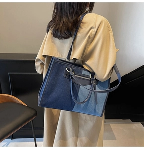 Detalle de un bolso tote grande de patchwork con texturas de denim azul y correas dobles