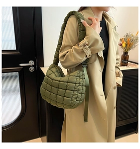 Detail of army green quilted cloud bag with wide padded strap on a beige trench coat