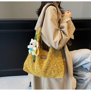 Close-up of ginger yellow plush tote bag with leather straps and bear charm