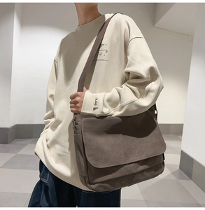 Braune Messenger-Tasche aus Canvas an einem Modell mit beigem Sweatshirt