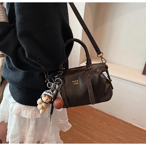 Detail of dark brown Boston bag with Pan Tor logo, bear charm and basketball pendant
