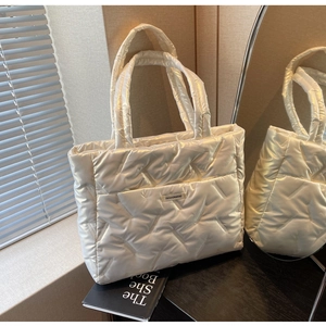 Détail du sac fourre-tout matelassé crème avec texture géométrique et étiquette mode