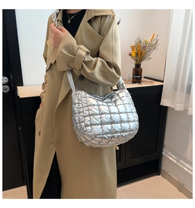 Detail view of a metallic silver quilted puffer shoulder bag with stylish textures