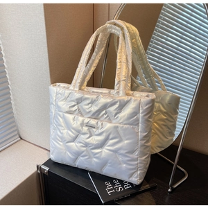 Détail d'un sac cabas matelassé blanc avec texture géométrique et étiquette tendance