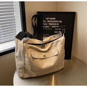 Detail der beigen Segeltuch-Umhängetasche mit Doppelreißverschluss und Frontklapptasche