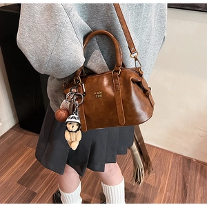 Detailed side view of vintage brown crossbody bag with plush teddy bear and basketball charms