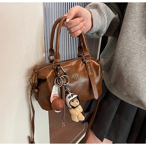 Detail of vintage brown baseball bag with logo and cute plush bear charm accessories