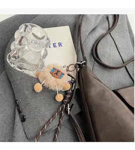 Borsa a tracolla vintage marrone con ciondolo in peluche su blazer grigio elegante